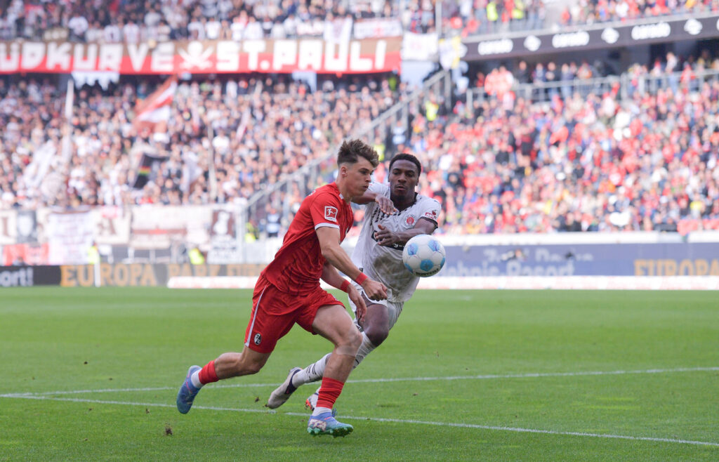 Freiburgs Noah Weißhaupt im Duell mit St. Paulis Oladapo Afolayan